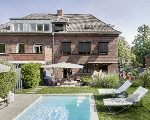 Modernes Backsteinhaus mit Pool und Liegestühlen im Garten