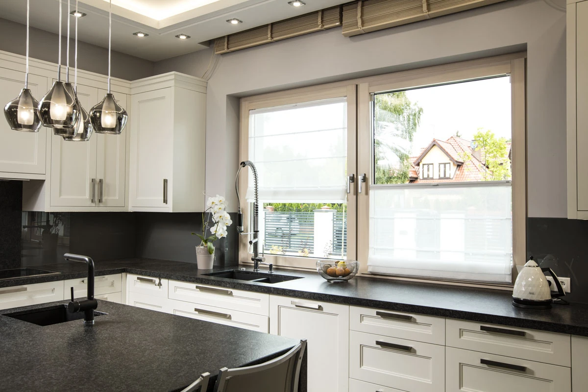 Moderne Küche mit Mittelinsel und großem Fenster mit Raffrollos
