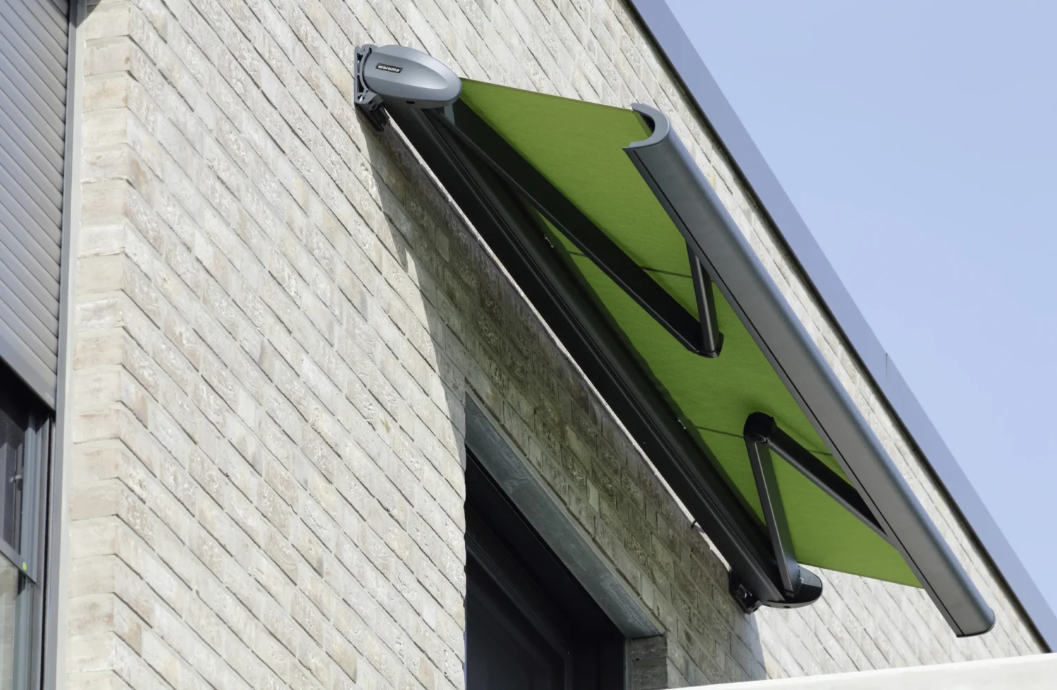 Grüne Markise an einer Steinwand